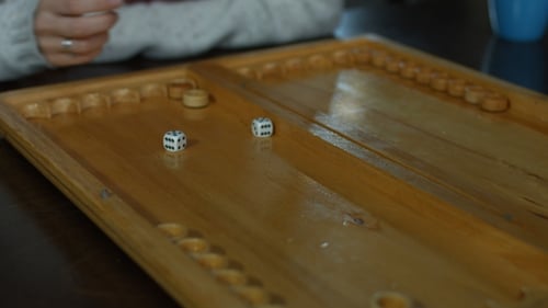 Playing Backgammon on a Wooden Table with Dice