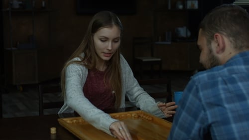 Chica encantadora y alegre jugando al backgammon en casa