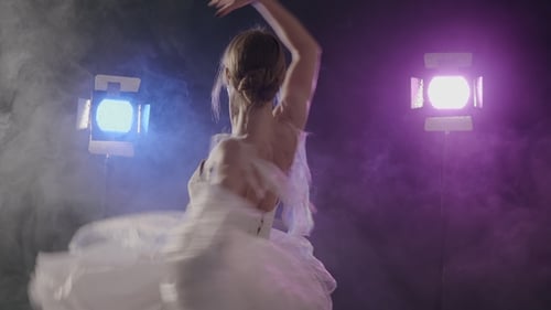 Elegant Ballerina Dancing in Stage Lights and Smoke