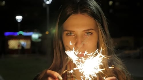 Smiling Young Woman Holding Sparklers at Night