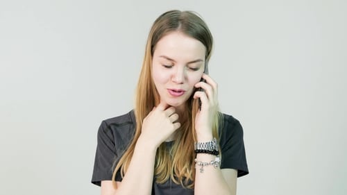 Young Woman Smiling and Talking on Her Cell Phone on a White Background. Front View of a Young
