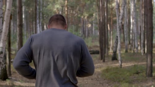 Male Runner Running Along a Nature Trail Through the Woods View From Back. Male Athlete Running