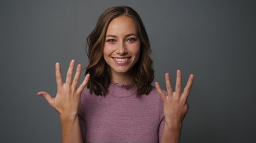 Smiling Woman Counts to Ten With Hands