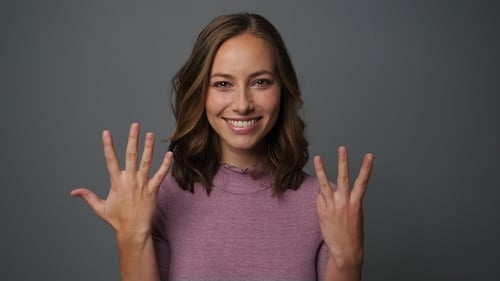 Woman Smiling and Showing the Number Eight