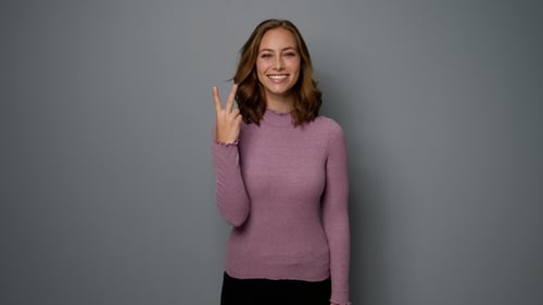 Smiling Woman Posing in Front of Gray Background