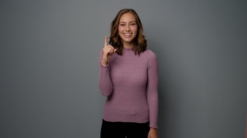 Smiling Woman Points Upward with an Idea