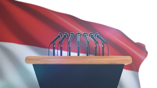 Waving National Flag Behind Podium with Many Microphones