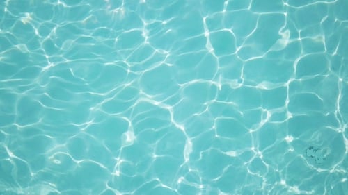 Water in Swimming Pool Rippled Water Detail Background. Water in Swimming Pool with Sun Reflection