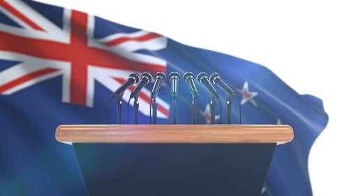 New Zealand Flag Waving Behind Podium with Microphones for Official Announcement