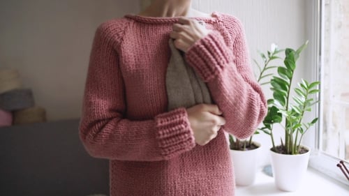 Woman Holding Knitted Item in Cozy Home Setting