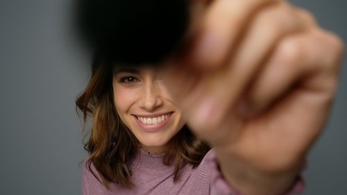 Woman Applying Makeup with Brush in Studio