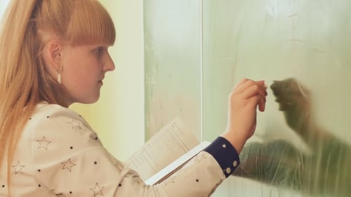 Woman Writing on Chalkboard in Classroom