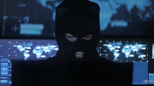 Un pirate informatique masqué tente d'entrer dans le système à l'aide de codes et de chiffres pour découvrir