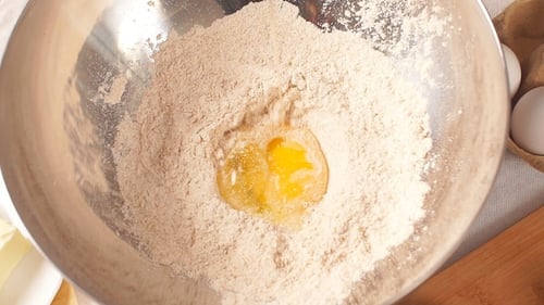 Egg Yolk Falls Into a Glass Bowl with Flour.