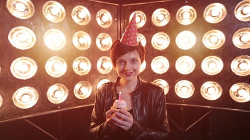 Young Woman Blowing Out Birthday Candle on Cupcake