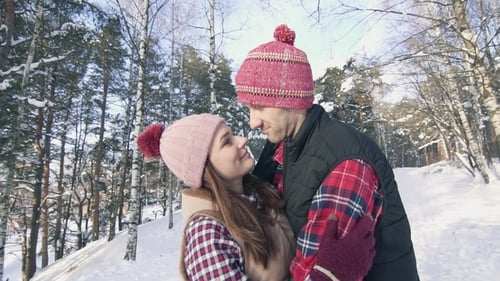 Beautiful Couple of Smiling Young People in Winter Clothes in a Snowy Forest
