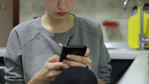 Young Woman Using Smartphone While Doing Homework