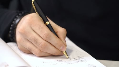 Person Writing in Notebook with Pen Close Up