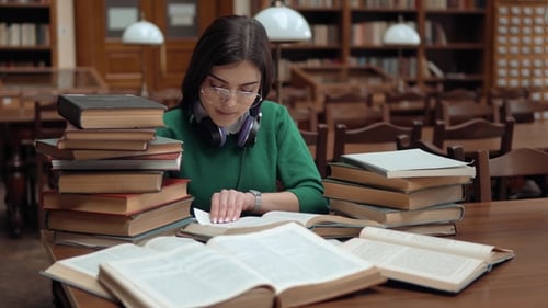 Young Woman Studying Surrounded by Books in Library