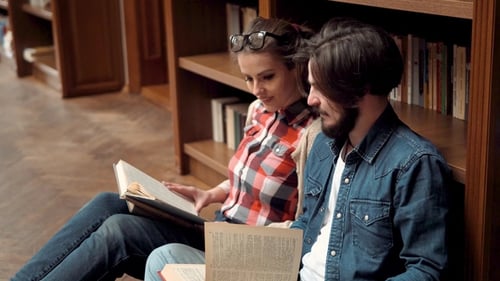 Couple Reads Books Together in Library