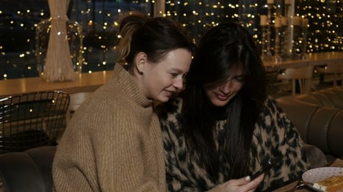 Two Women Using a Smartphone in Cozy Restaurant