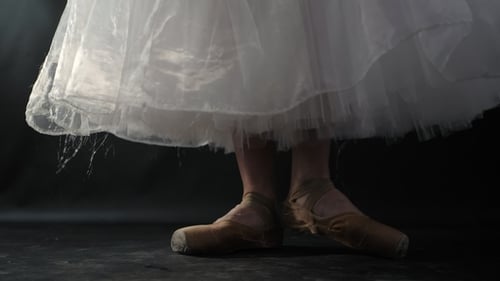 of Ballet Dancer As She Practices Exercises on Dark Stage or Studio. Woman's Feet in Pointe Shoes