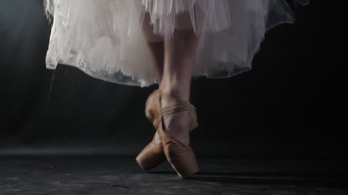 of Ballet Dancer As She Practices Exercises on Dark Stage or Studio. Woman's Feet in Pointe Shoes