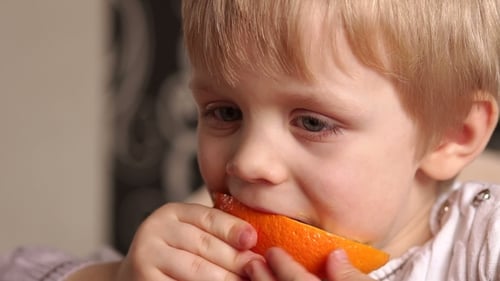 Petit garçon mangeant une orange mûre juteuse
