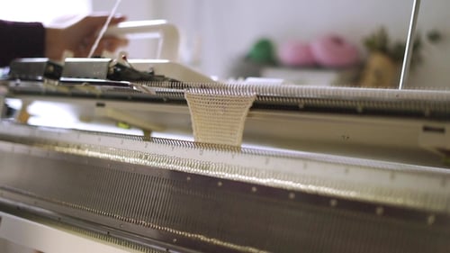 Weibliche Hände bei der Arbeit an der Webmaschine in der Werkstatt
