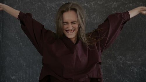Expressive young woman dancing and moving arms indoors
