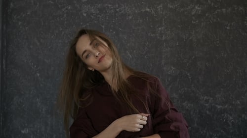 Woman Dancing and Gesturing in Front of Wall