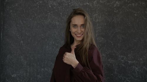 Young Woman Gives a Thumbs Up and Smiles