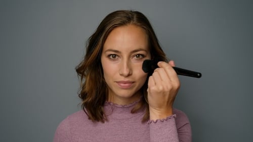 Woman Applies Makeup with Brush Close Up