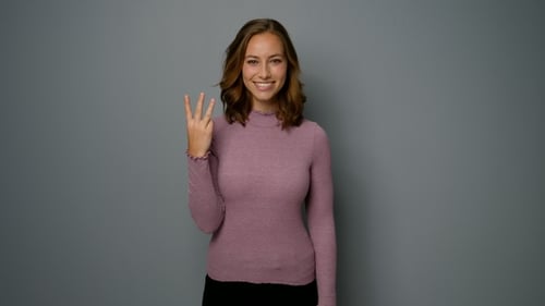 Smiling Woman Holds up Three Fingers