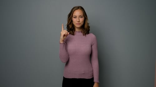 Smiling Woman Points Upwards in Studio Setting