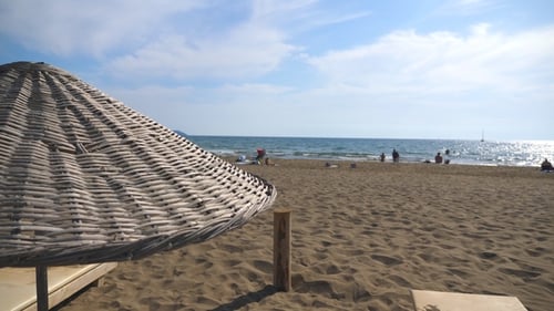 Beautiful View of Seascape and Beach with Deck Chair Under Straw Sun Umbrella on a Sunny Day