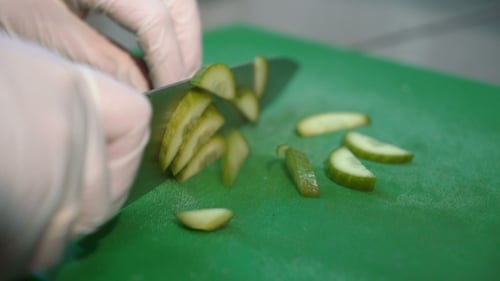 Pickles being sliced on a green cutting board
