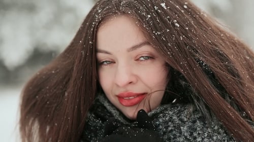 A Beautiful Young Girl with Chic Long Hair Is Enjoying Falling Snow in Winter