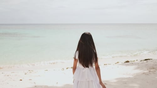 A Charming and Happy Philippine Teen Girl in a White Summer Dress Barefoot on a Tropical Beach