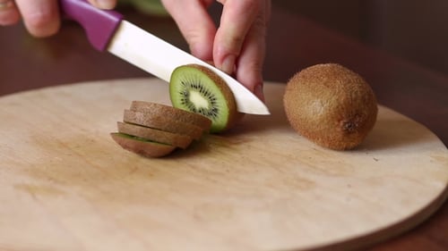 Slicing a Ripe Kiwi on Wooden Board