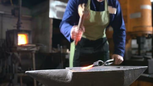 Blacksmith Forging Metal at Anvil in Workshop