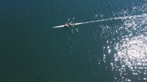 Ruder-Trainingsantenne. Ruder-Trainings-Antenne. Mann und Frau paddeln mit funkelndem blauem Wasser