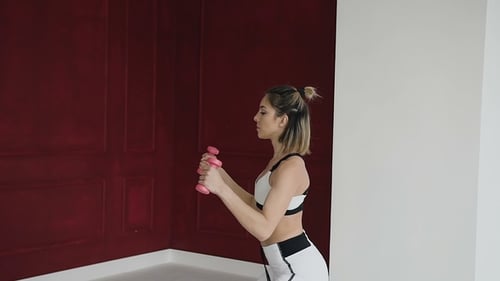 Athletic Woman Curls Dumbbells in Home Gym