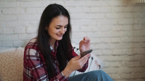 Smiling Woman Using Mobile Phone at Home