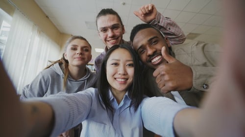 Smiling Young Adults Take Group Selfie Indoors