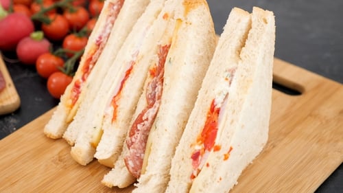 Club Sandwich on a Wooden Board Next To Meat Appetizers