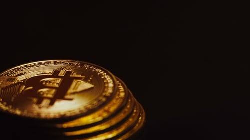 Aufnahme von leuchtend goldenen Bitcoins, die in einer Säule liegen und sich drehen
