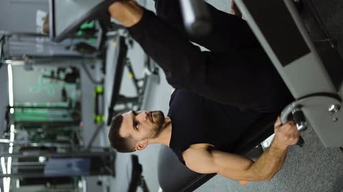 Vertikales Video eines muskulösen Mannes führt Übungen an einem Sporttrainingsgerät für die Beinmuskulatur durch