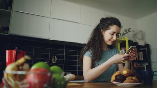 Young Woman Using Smartphone in Modern Kitchen