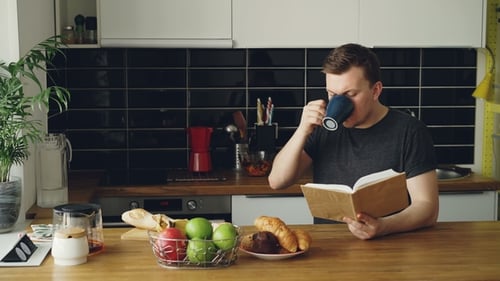 Young Adult Reads Book and Drinks Coffee